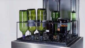 Green wine bottles in a bottle washer basket