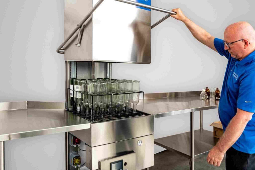Operador utilizando una lavadora comercial de botellas de vino