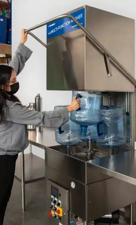 Opératrice chargeant des bonbonnes de 18,9 L (5 gal US) dans une laveuse MFW